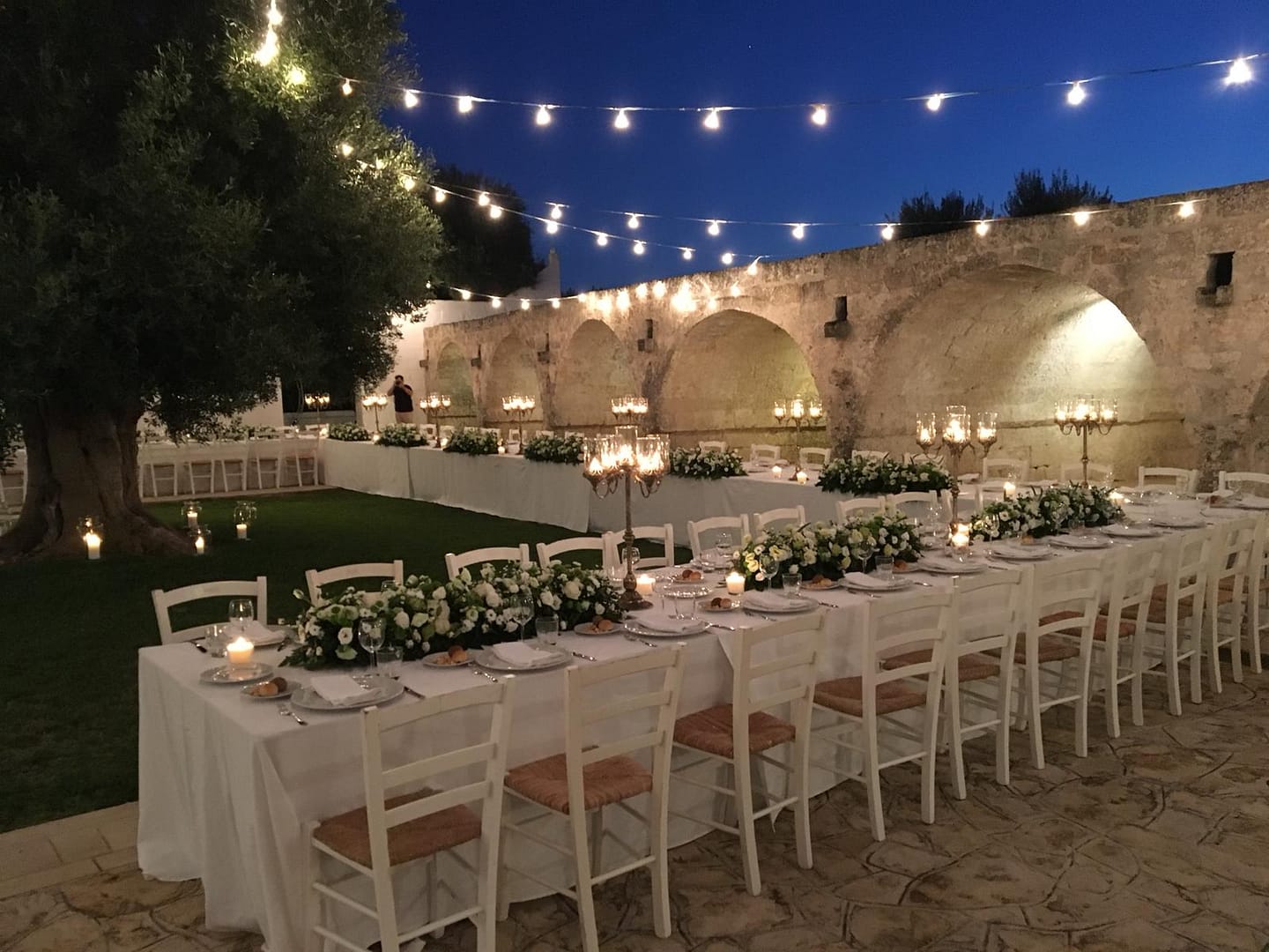 Wedding banquet in a Puglian masseria.  Long tables set up under fairy lights.