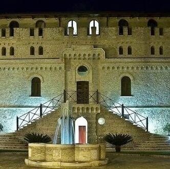 Facade of a castle with a fountain in front.