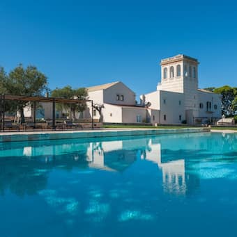 White wasseria in Puglia with a sunny blue sky behind and blue swimming pool in front.