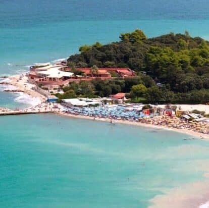 Seaside wedding venue with green trees behind it and the beach/sea in front.