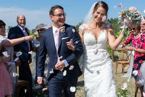 Jess and Mike walking through a vineyard during their wedding