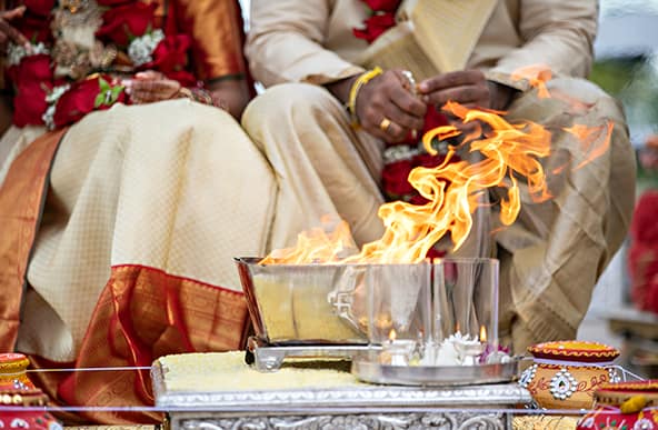 Close-up of fire tray at a Hindu wedding ceremony. The bride and groom's knees can be seen behind.
