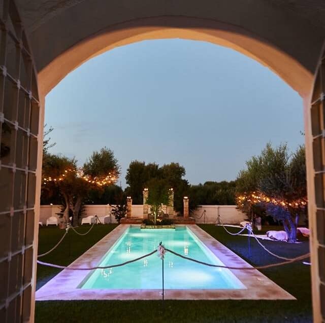 Tall cream coloured villa on top of a cliff above the sea.