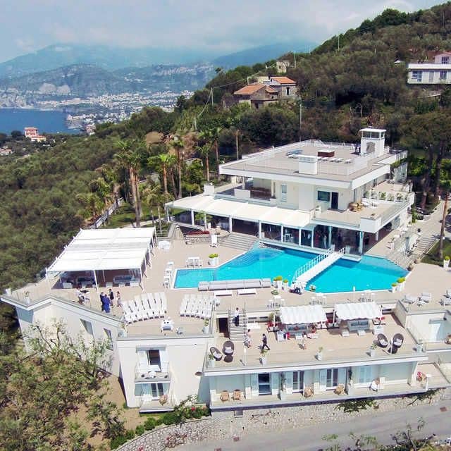 Wedding venue on a wooded hill side high above Sorrento.  There are three white buildings around a swimming pool.