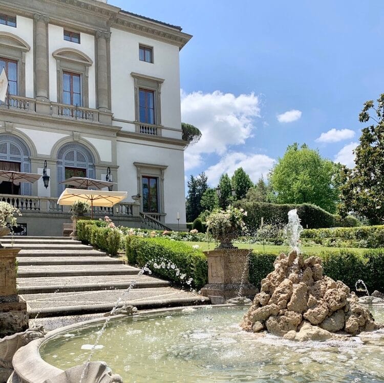 Aerial view of Villa Tolomei in Florence.  There is e lawn around the villa.  There are outbuildings also around the lawn and a swimming pool can be seen behind the villa.