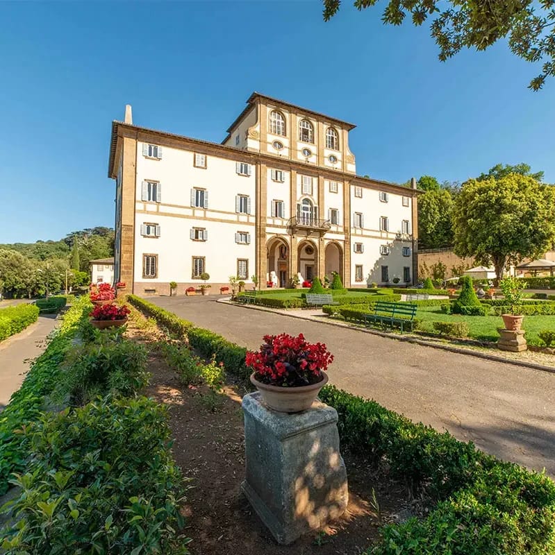 Large wedding villa in Rome.  The facade of the palace is photographed across the large pristine front garden.
